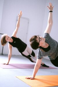 twee vrouwen die in een plankhouding op een fitness matje bezig zijn om te sporten